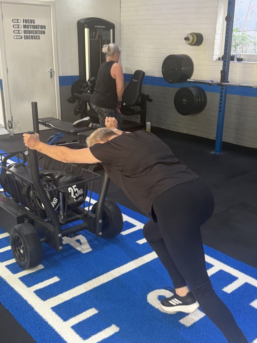 SPS Fitness member pushing the weighted sled during a small group training session