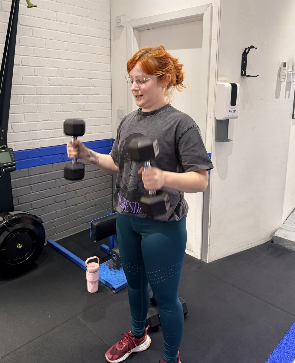 SPS Fitness member training with dumbbells, smiling during her session